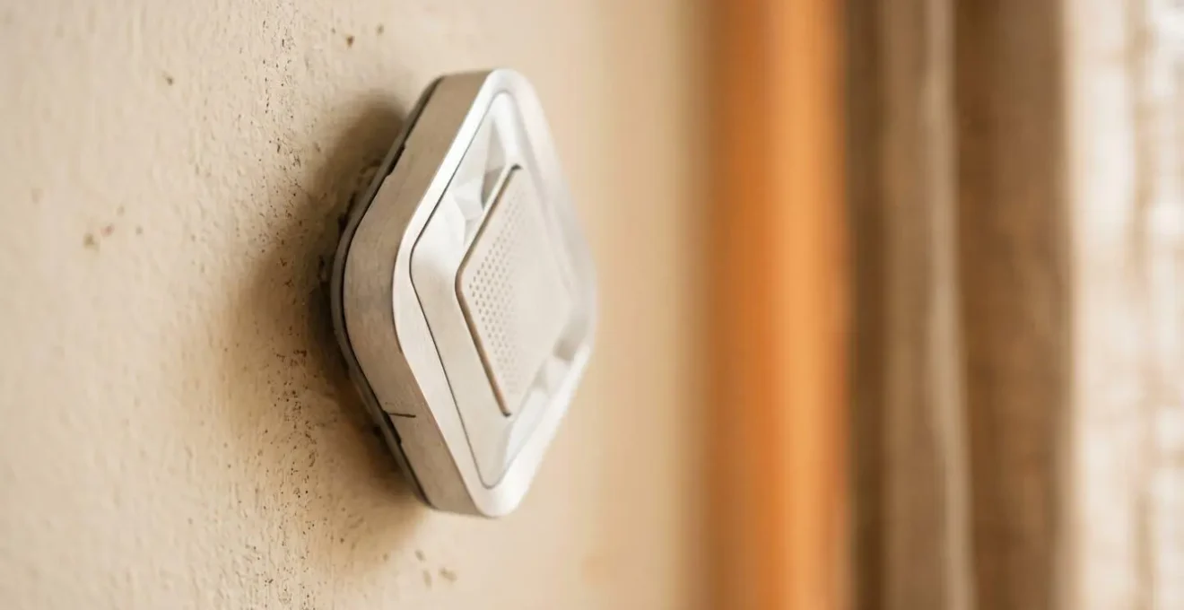 Détail macro d'un capteur de température et d'humidité moderne installé discrètement dans un intérieur chaleureux