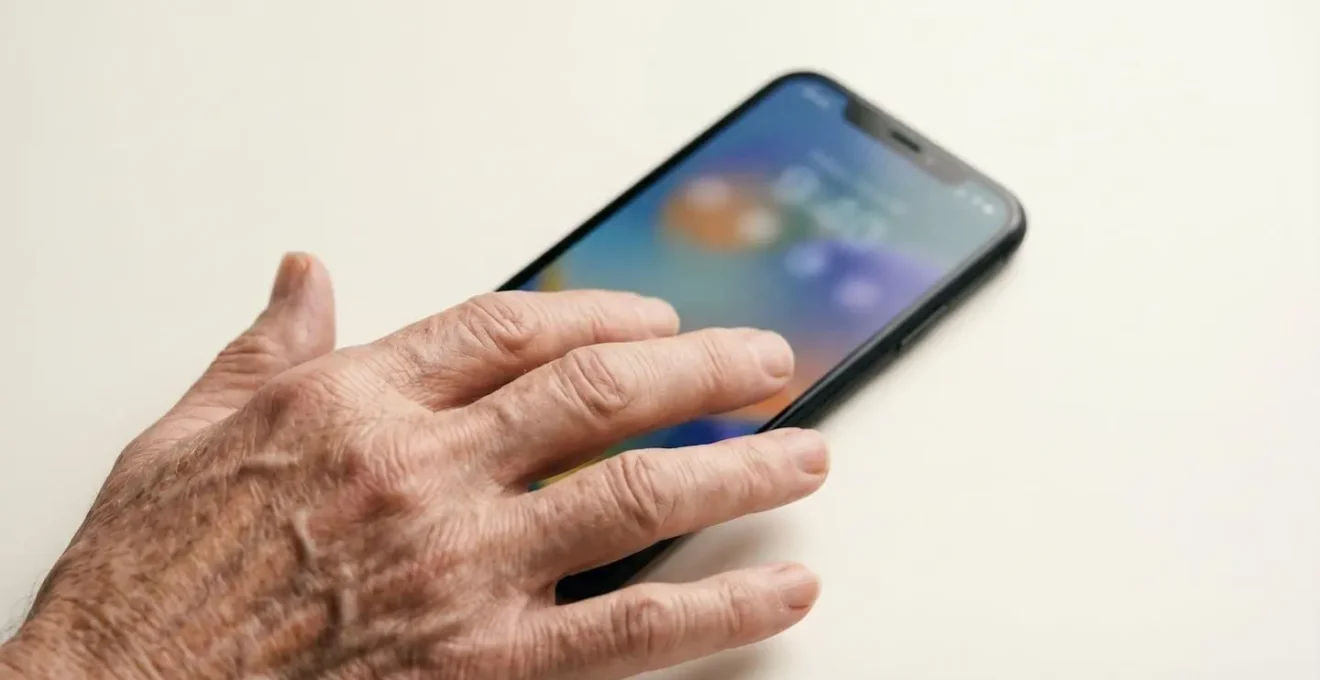 Gros plan sur un smartphone affichant un rappel médicament avec une main âgée à proximité
